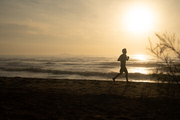 silhouette man run on beach with sunrise and sea background