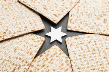 Jewish flatbread matza for Passover and Star of David on dark background