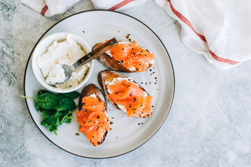 Delicious toast with salmon and cheese cream on a white plate whit spinach.