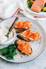 Delicious toast with salmon and cheese cream on a white plate whit spinach.