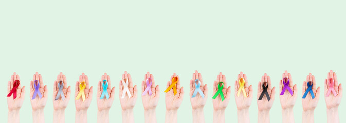 Women's hands hold multicolored ribbons, symbol of the fight against cancer. World cancer day