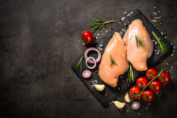 Chicken fillet with spices and herbs at black stone table. Raw meat, fresh meat. Top view with copy space.