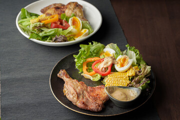 plate of delicious grilled chicken legs steak with vegetable salad on wooden table