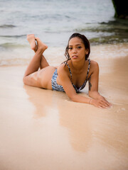 Beautiful woman lying on sandy beach near the ocean. Sexy body. Tanned skin. Asian woman wearing bikini. Summer concept. Vacation time. Travel lifestyle. Bali, Indonesia