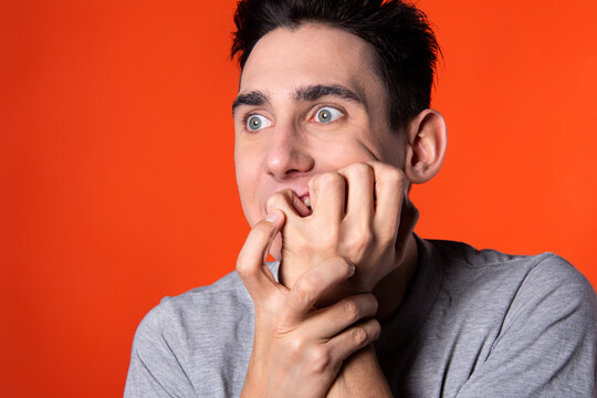 The young man is actively gesturing. Expression of emotions. Blue clothes. Orange background. Point of view.