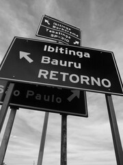 Group of metal signs indicating multiple locations in a confuse way at brazilian countryside [Black...