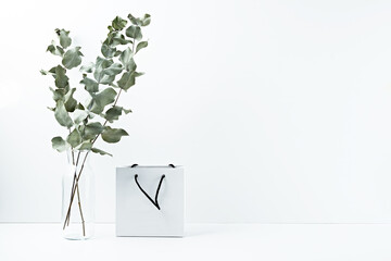 Gift bag and vase with dried flowers on a white background. Copy space, mock up.