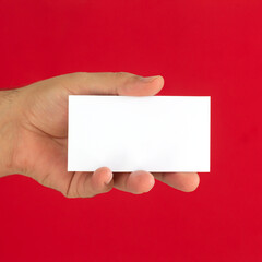 Male hand holding blank business card on red background