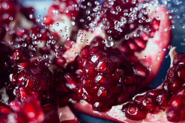 Macro shooting of delicious cut pomegranate fruit under drops of water.