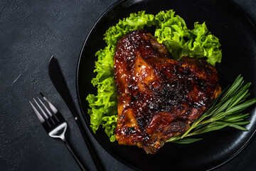 Roast turkey thigh with cranberry sauce and herbs. Top view at black table.