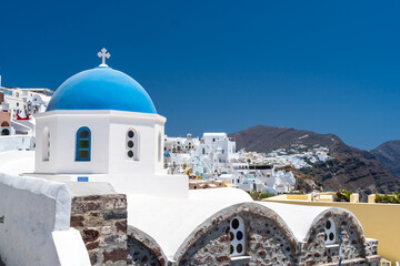 Famous Greek orthodox blue domed church and bell tower in Oia village on Santorini island, one of famous Greek Aegean Islands. Travel destination in Santorini, Greece.