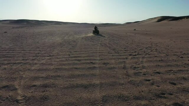 Aerial drone shot of man drifting quad bike in desert