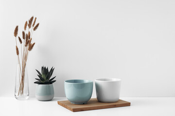 Mugs on a wooden stand, house plant, vase. Eco-friendly materials in the decor of the room, minimalism. Copy space, mock up.