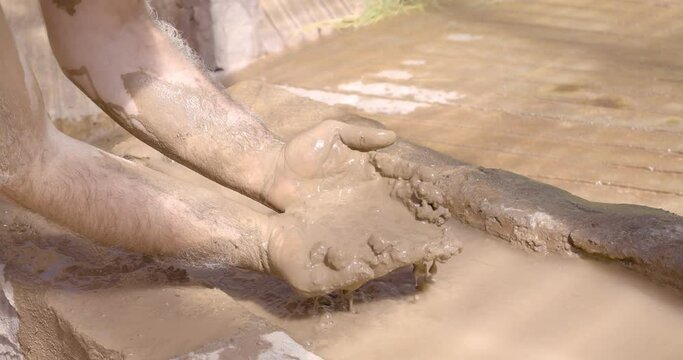 A man smears his skin with therapeutic cosmetic mud and clay from a natural lake. Cleaning face and body skin with spa cleansing mud. Skincare beauty treatment.