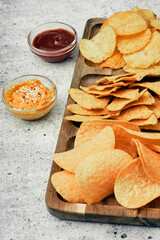 Chips, snacks and crackers on a wooden board. Fast food.