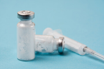 Syringe and ampoules with vaccine or medicine for covid 19 on a blue background