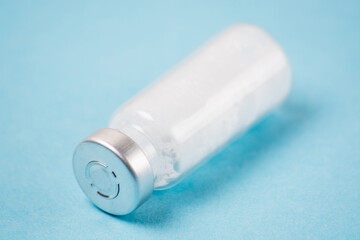Ampoule with a vaccine or medicine for covid19 close-up, copy space, on a blue background. The concept of vaccination of the population and the fight against disease.