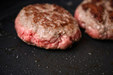 Hamburguesa de carne cruda en sartén negra con aceite