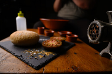 Plano de la elaboración de receta casera con carne fresca cruda de ternera, especias, tomate, pan y herramientas de cocina como la picadora antigua