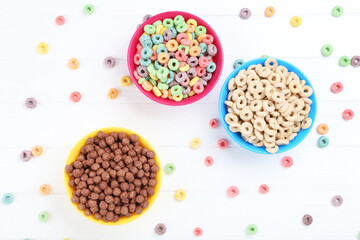 Various corn flakes in bowls on white wooden table