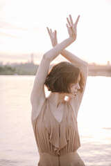 Fototapeta na wymiar young woman posing and yoga dancing near beach at sunset