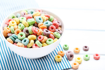 Colorful corn rings in bowl on white wooden table
