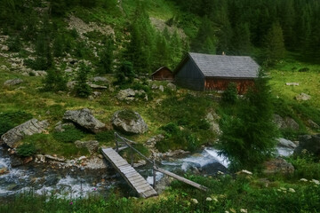 wooden house with a bridge over a mountain brook while hiking