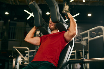 Athletic man doing legs exercise on squat machine at the gym  focus on the upper body