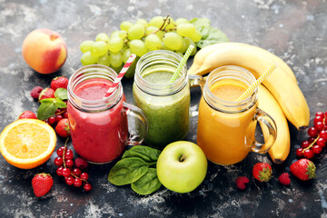 Fresh smoothies in glass jars with fruits and vegetables on wooden background