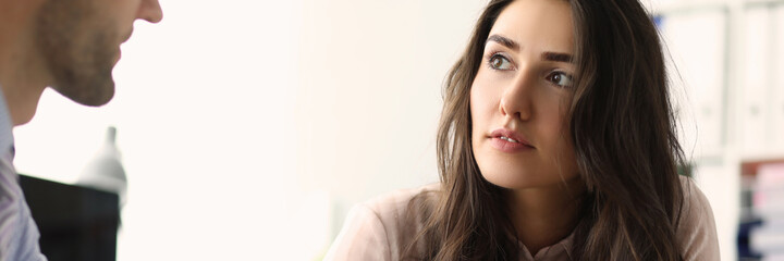 Obraz premium Two young employees looking at each other in the office while talking. Teamwork and partnership concept