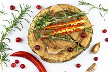 Branches of rosemary, berry of cranberry, sharp pepper, garlic on wooden support isolated on a white background.