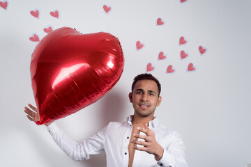 Happy man with a red heart balloon flying between his hands, and heart papers flying behind him, white background. love and Valentine concept 