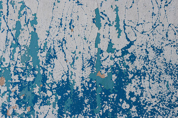 Fototapeta premium Peeling paint on the wall. Old concrete wall with cracked flaking paint. Weathered rough painted surface with patterns of cracks and peeling. High resolution texture for background and design. Closeup