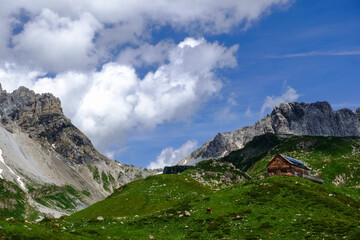 Fototapeta na wymiar wooden alpine cabin in rocky mountains with blue sky