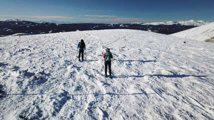 Fototapeta na wymiar A drone shot of a couple wearing snow shoes hiking up to the peak of Speikkogel in Austrian Alps. The whole slope is covered with snow. many mountain chains in the back. Winter outdoor activity. Fun