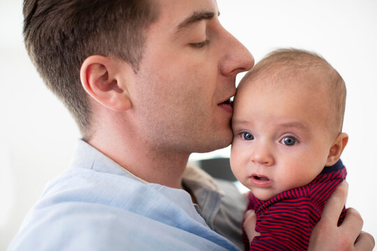 Close Up Of Loving Father Cuddling And Kissing Baby Son At Home