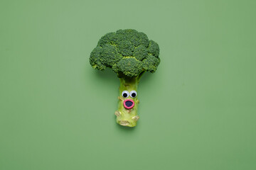 Shocked looking broccoli with googly eyes and mouth on a matching green background with copy space...
