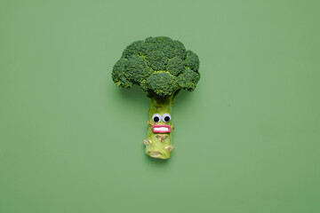 Scared looking broccoli with googly eyes and mouth on a matching green background with copy space...