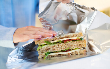 Close Up Of Woman Wrapping Sandwich In Non Reusable Aluminium Foil