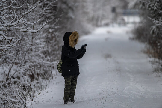 girl photographing winter forest landscape