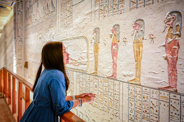 Luxor, Egypt - 02 11 2020: Asian women stand to admire the beauty of the ancient and mysterious Egyptian wall carving inside the cemetery in The Valley of the Kings.