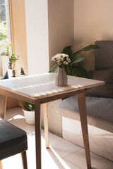 White flowers arranged in a ceramic vase, Was placed on a wooden table In the corner of the room where the sunshine was warm.