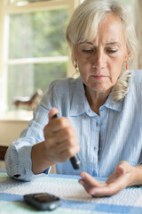 Senior Diabetic Woman Testing Blood Sugar Level At Home