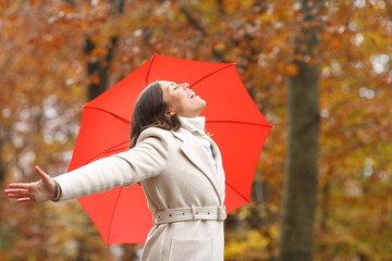 Happy middle aged woman breathing in winter with umbrella