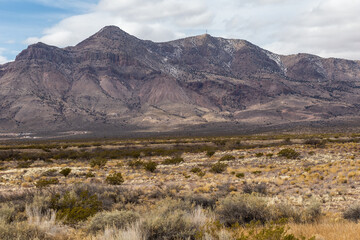 Light brushes of snow on mountain scape behind vast desert vista landscape in rural New Mexico