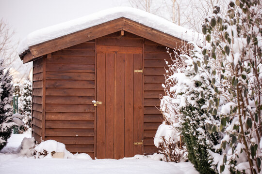 Drewniany domek altanka zimą w ogrodzie przykryta śniegiem