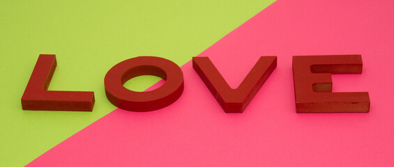 Valentine's day, red wooden letters love on green-pink background, banner format
