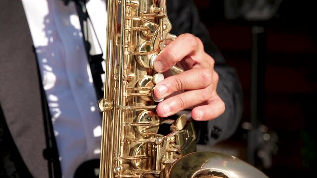 Hands playing the saxophone. Saxophonist plays jazz and love music.