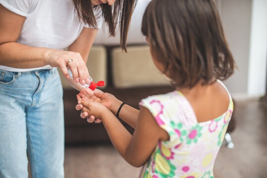 Mother putting sanitizer on young girl's hands