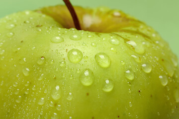 Close up of water drops on fresh green apple, small depth of focus.